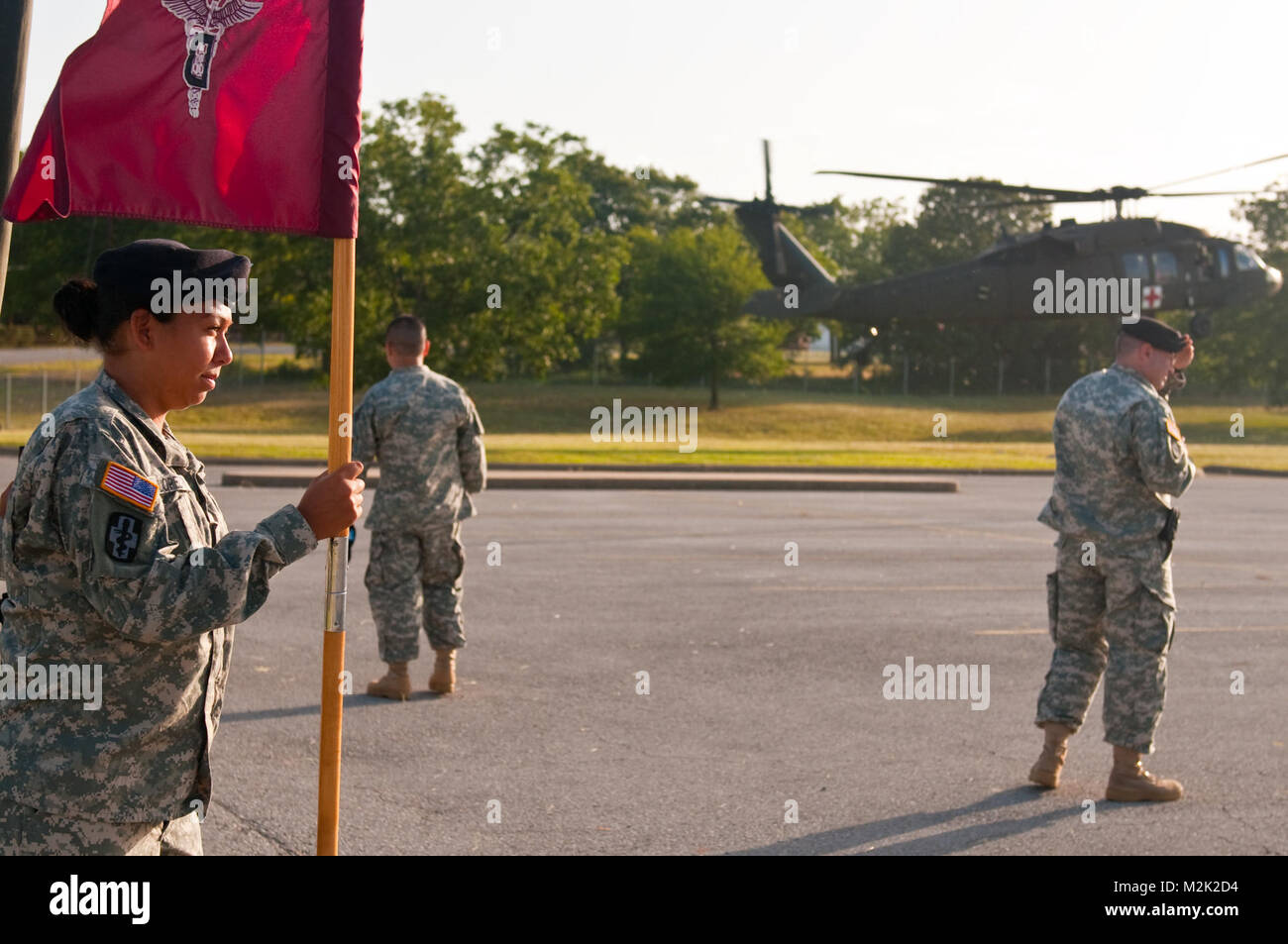 Spc. Brenda Lopez, an Army dental hygenist and a native of Dallas, Texas clings to the guidon of the 965th Dental Company as a UH-60 Blackhawk Helicopter lands nearby.  Lopez is participating in her first official ceremony as an Army Reservist. Hanging onto the Guidon by 807MCDS Stock Photo