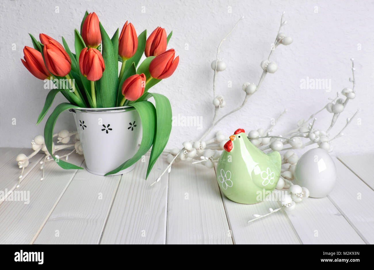 Easter greeting card design with bunch of red tulips, ceramic hen and egg on light spring background with paper flowers Stock Photo