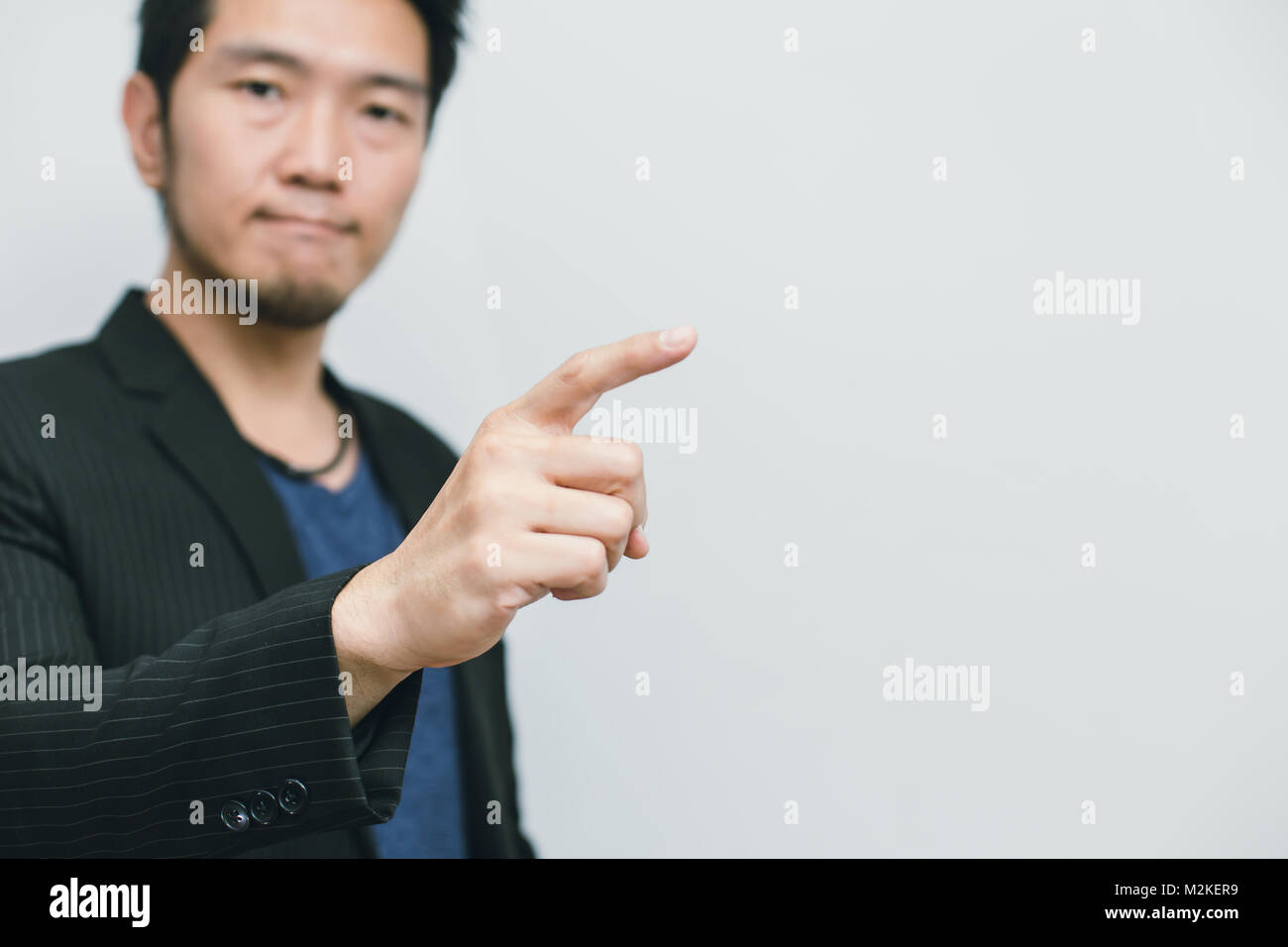 Asian business man point finger at side way to focus at white space for quote text Stock Photo
