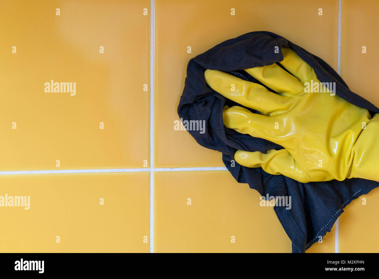 hand in a yellow rubber glove washes a yellow wall with a rag Stock ...