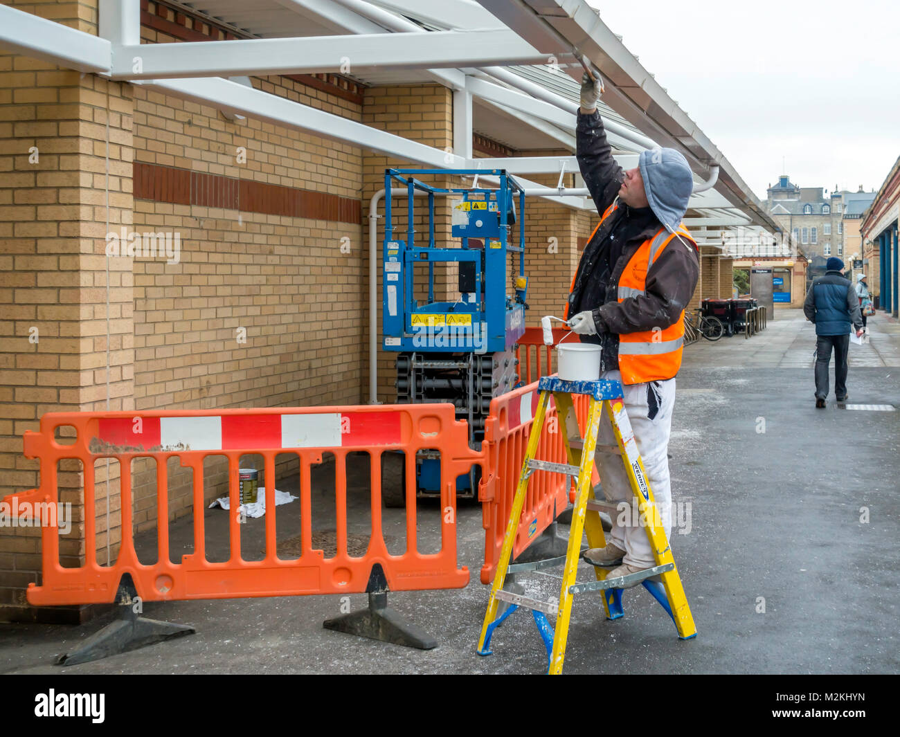 A decorator painting the exterior of a Supermarket in Saltburn by the Sea North Yorkshire Stock Photo