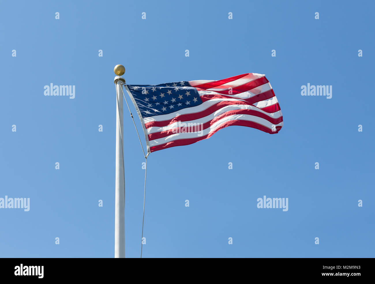 The United States flag on blue sky background, turned to the right Stock Photo