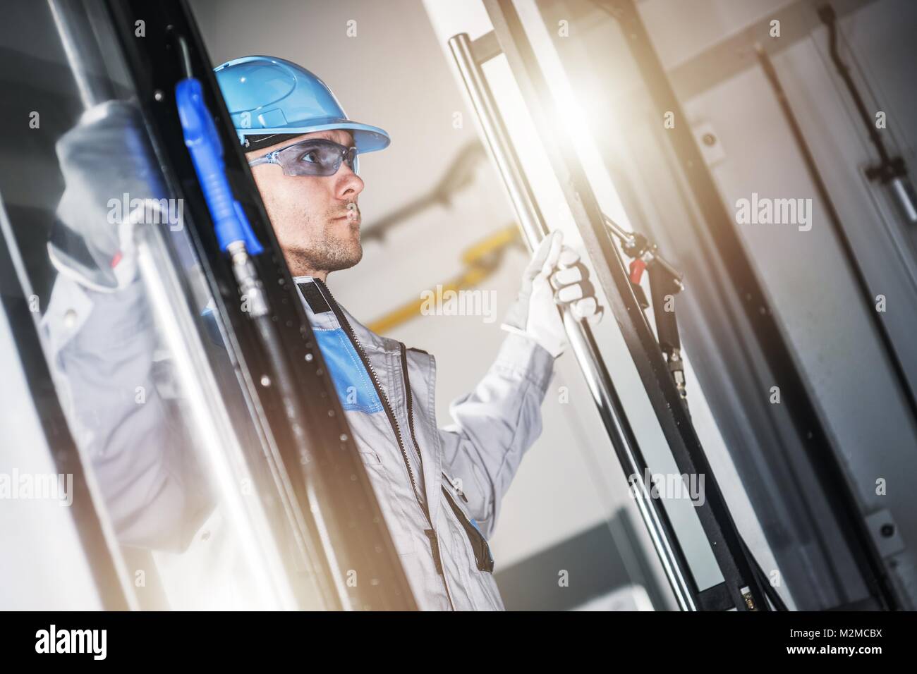 Caucasian CNC Technician Taking Look Inside the Modern CNC Machine. Metalworking Industry Concept. Stock Photo