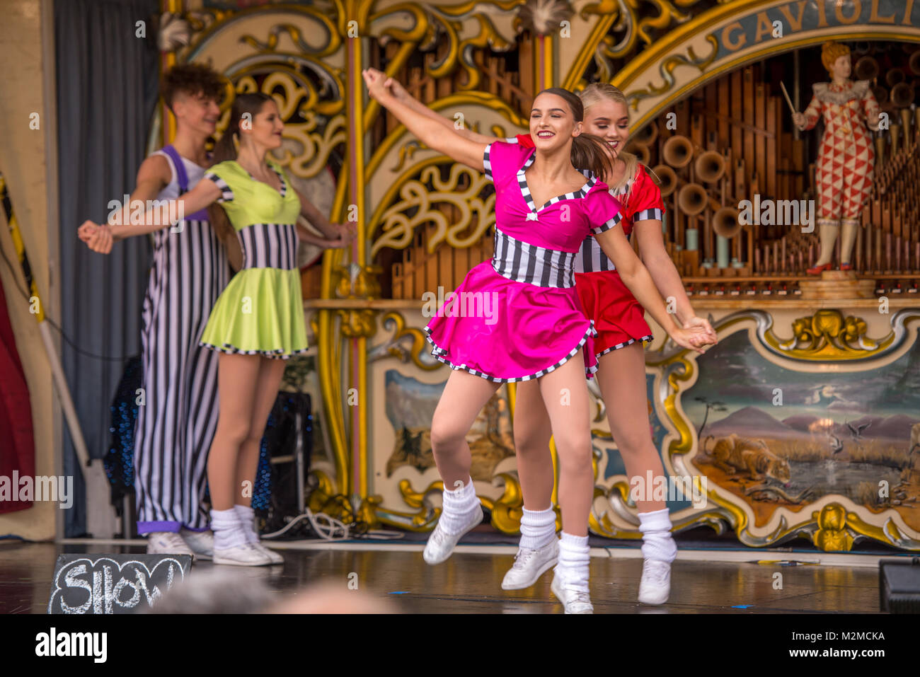 Dancers in colorful costumes dance with joy on top of fairground organ, Masham, North Yorkshire, UK Stock Photo