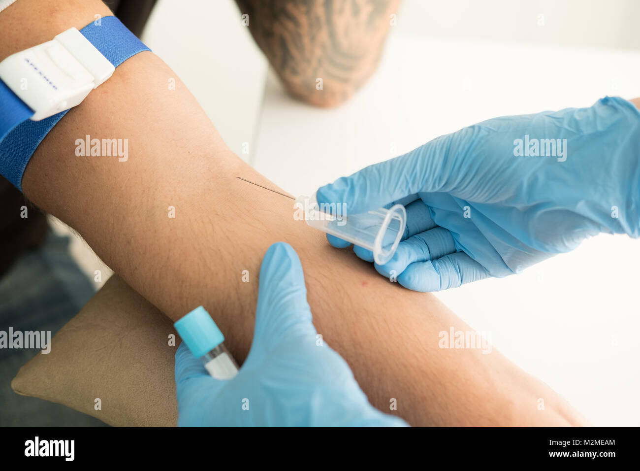 Close up nurse pricking needle syringe in the arm patient drawing blood sample for blood test Stock Photo