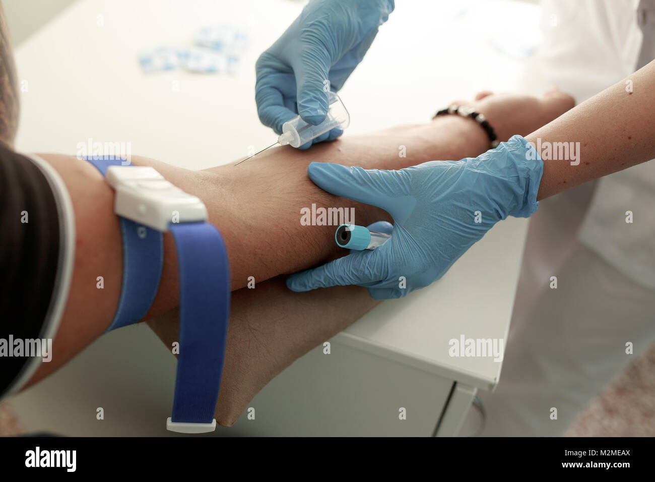 Close up nurse pricking needle syringe in the arm patient drawing blood sample for blood test. Close up Stock Photo