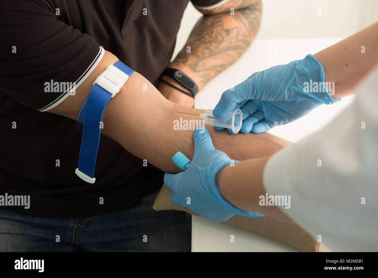 Close up nurse pricking needle syringe in the arm patient drawing blood sample for blood test. Close up Stock Photo