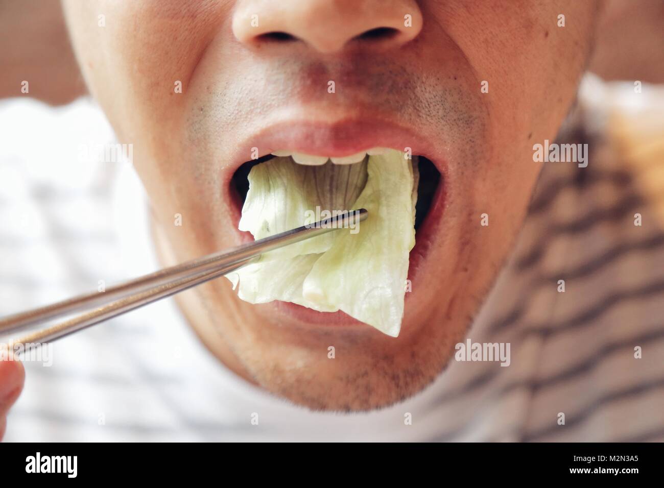 Closeup Asian male eating fresh vegetable food,Napa cabbage, in Chinese style with chopstick. Show concept and idea of healthy. Stock Photo