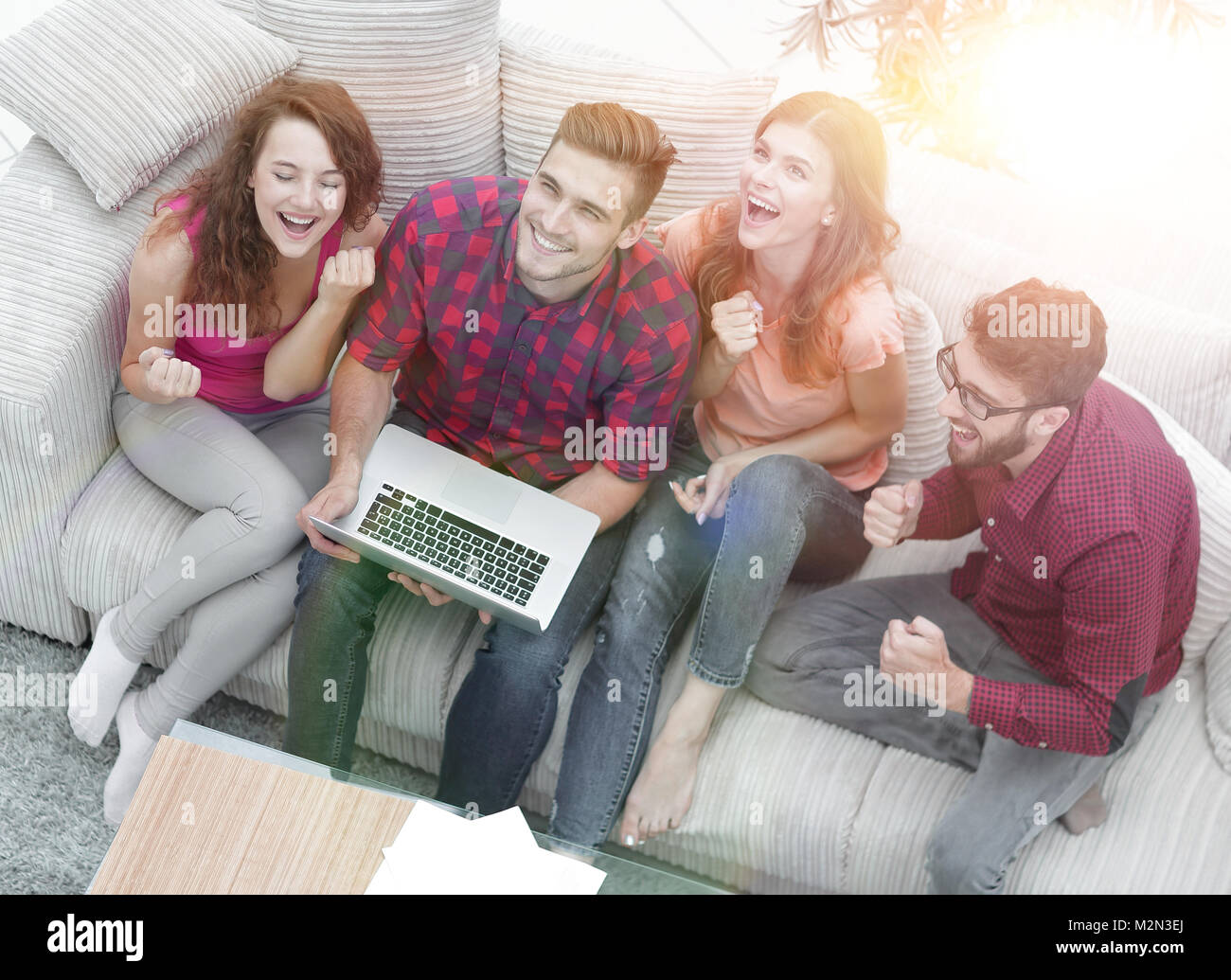 triumphant group of friends laughing while sitting on the couch in the ...