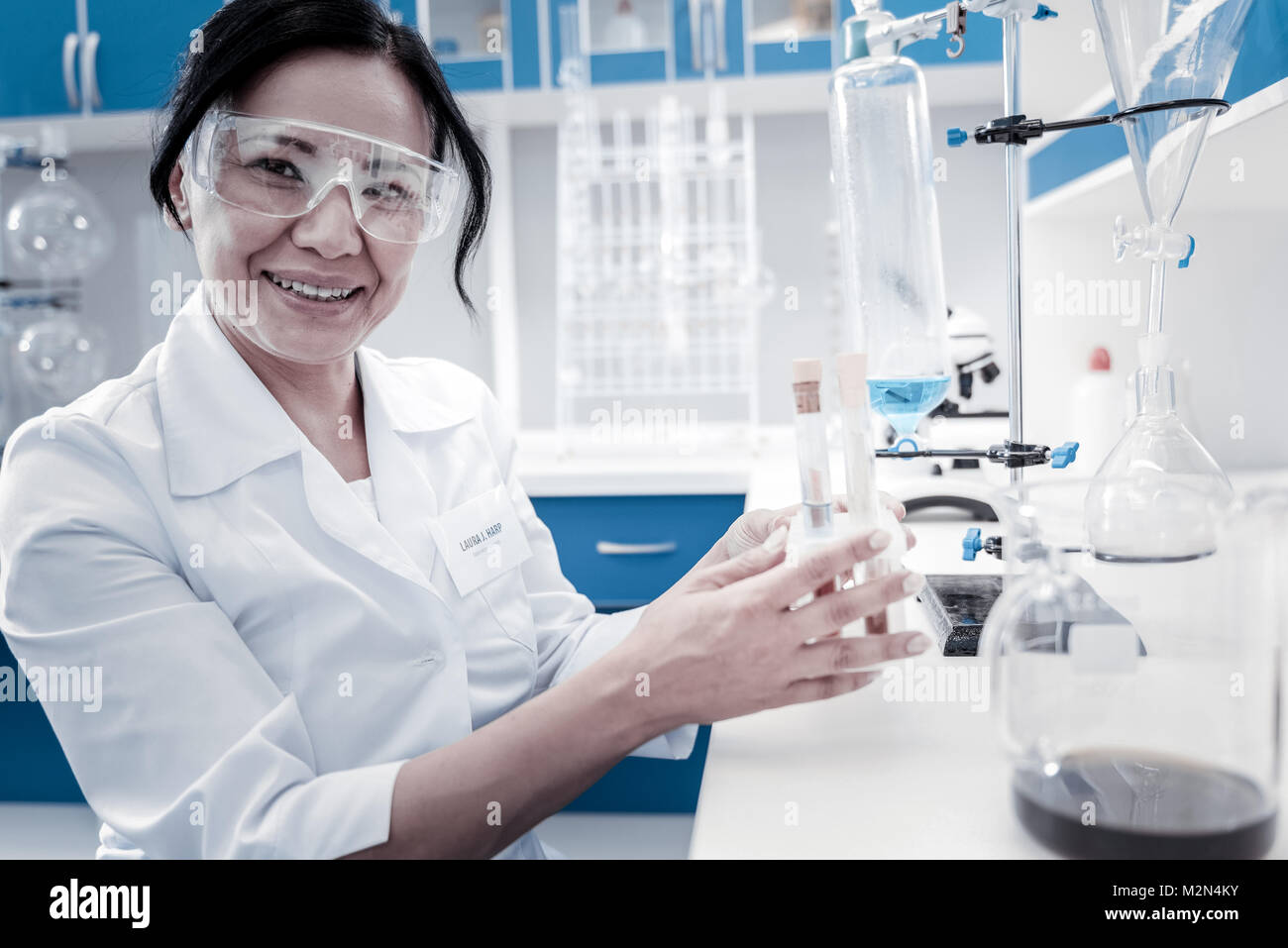 Joyful female scientist smiling while holding test tubes Stock Photo