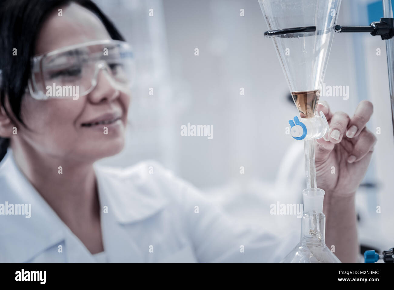 Cheerful scientist regulating lab glassware fixed on metal stand Stock Photo