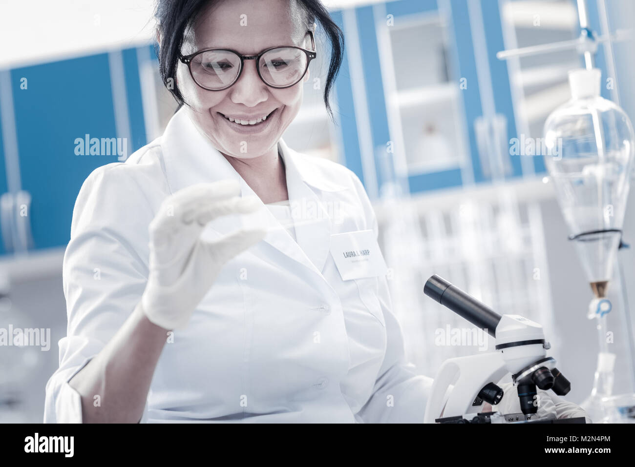 Happy scientist smiling while looking at microscope slide Stock Photo