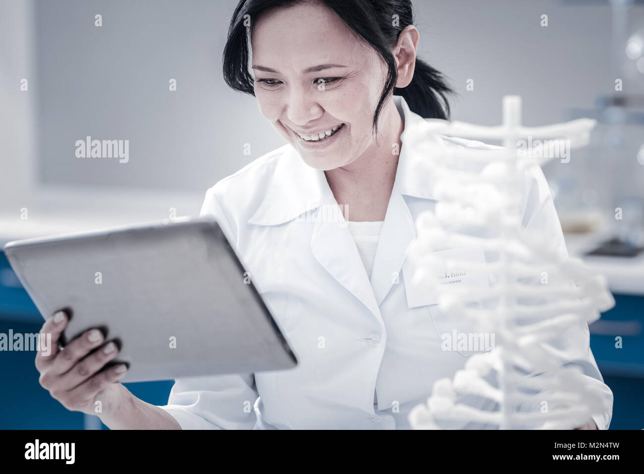 Satisfied female scientist smiling while looking at tablet computer Stock Photo