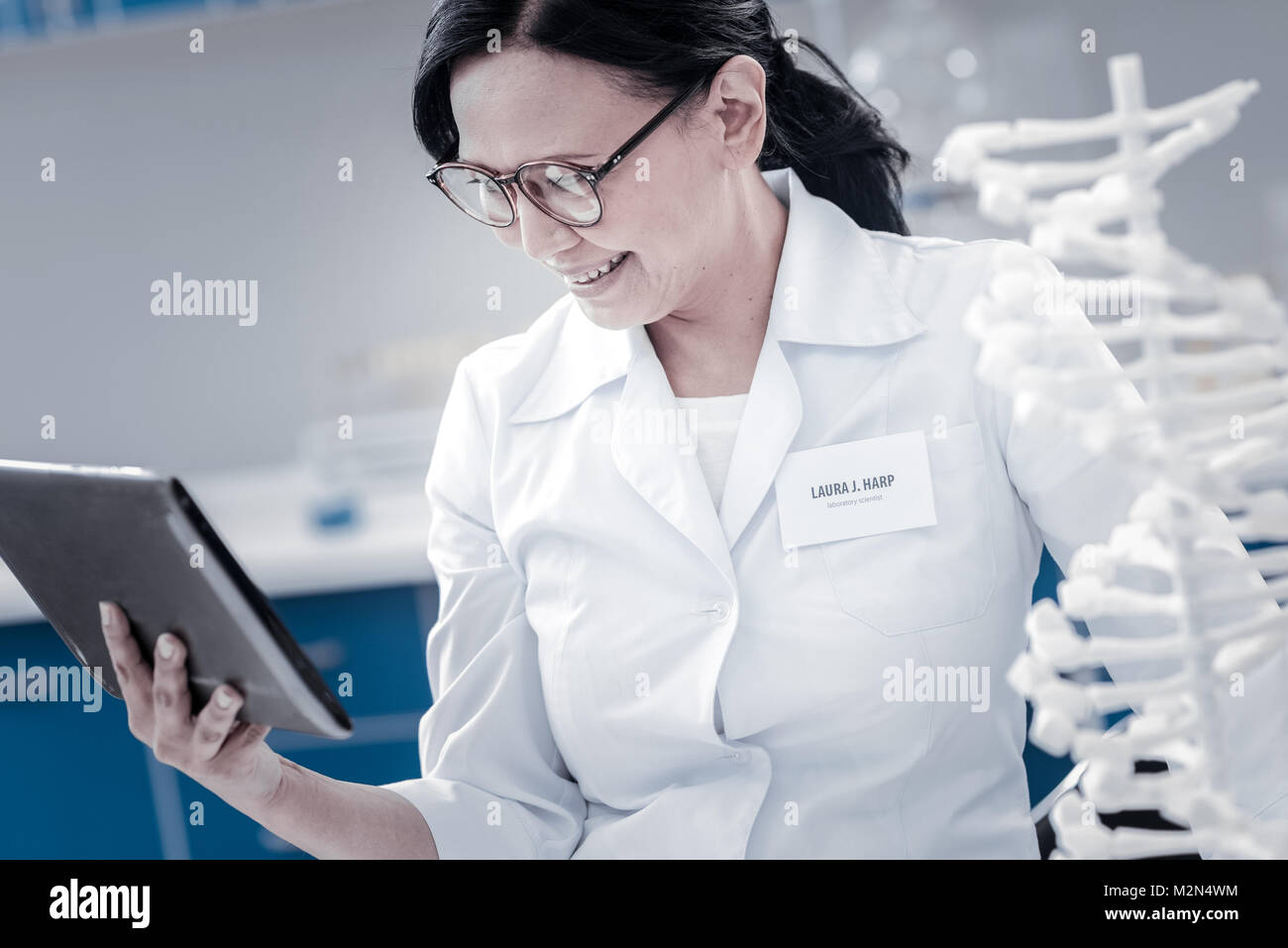 Smiling genetic scientist working on touchpad in lab Stock Photo