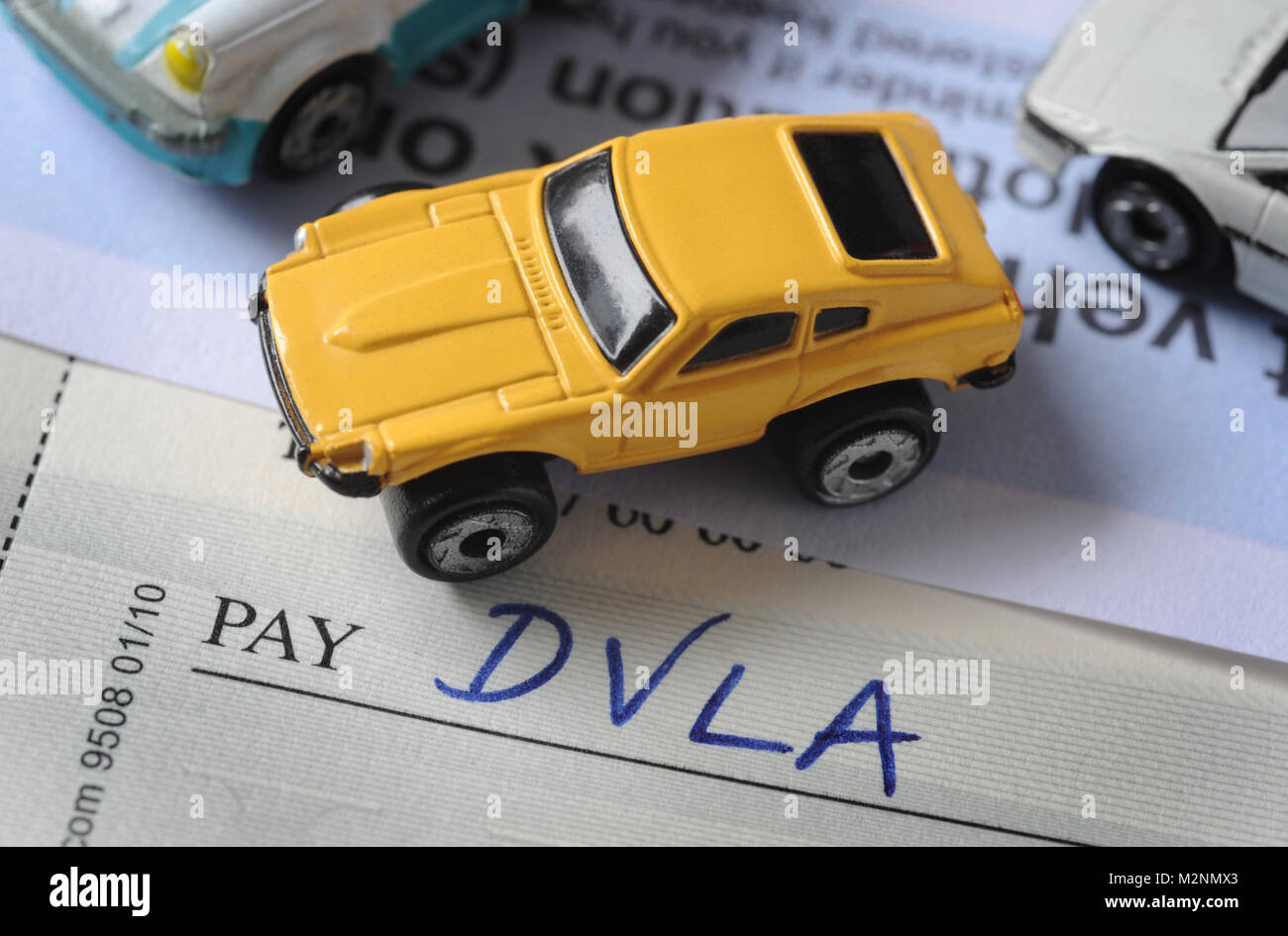 'DVLA'  WRITTEN ON CHEQUE BOOK WITH MODEL CAR RE DVLA DRIVER VEHICLE LICENSING AGENCY ROAD TAX EXCISE LICENSE MOTORISTS ETC Stock Photo