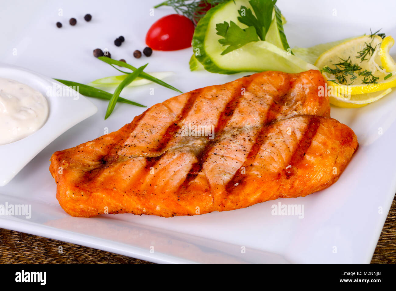 Grilled salmon with sauce served lemon Stock Photo - Alamy