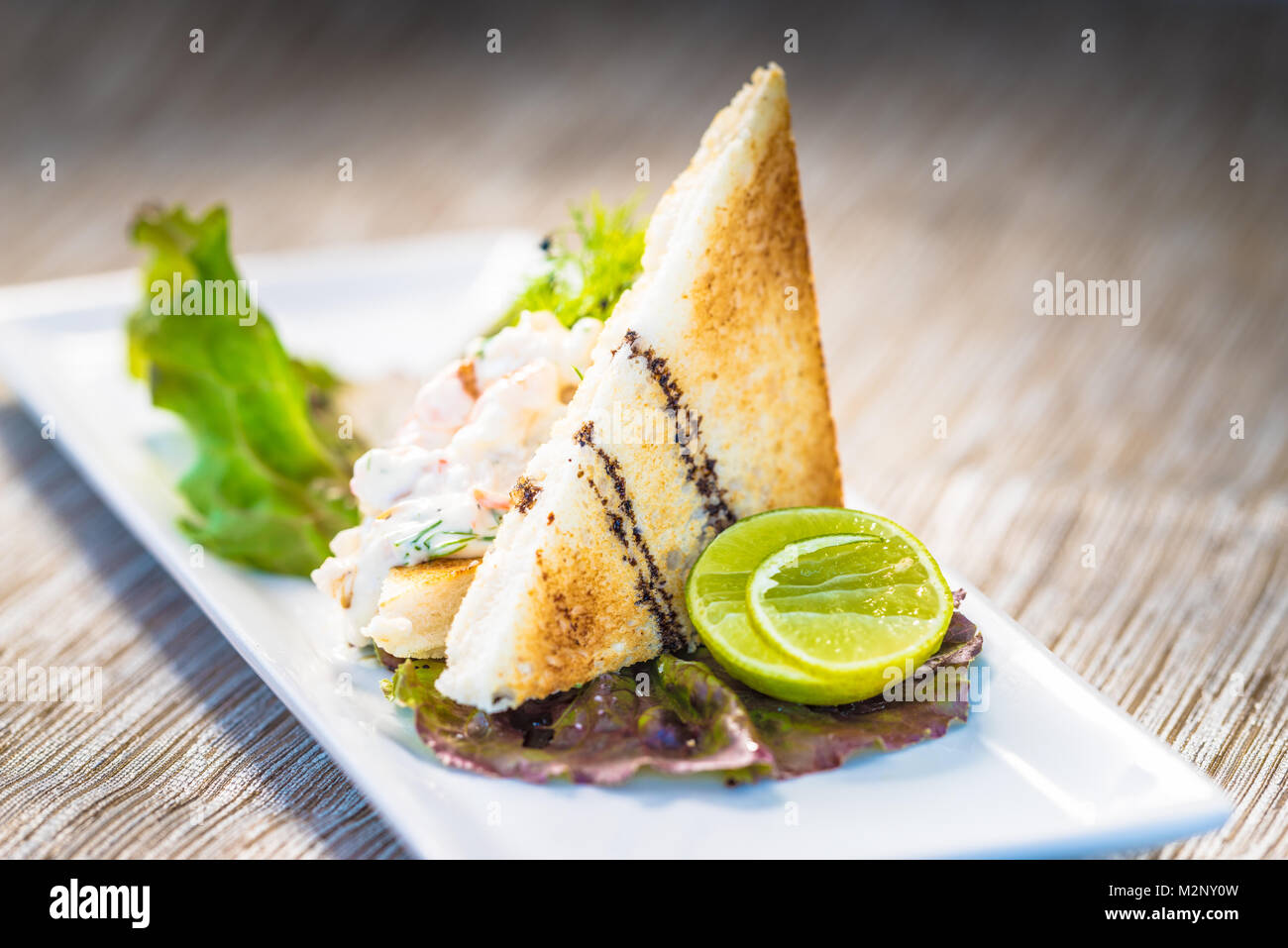 Fine dining toast with shrimps, lettuce and lime Stock Photo