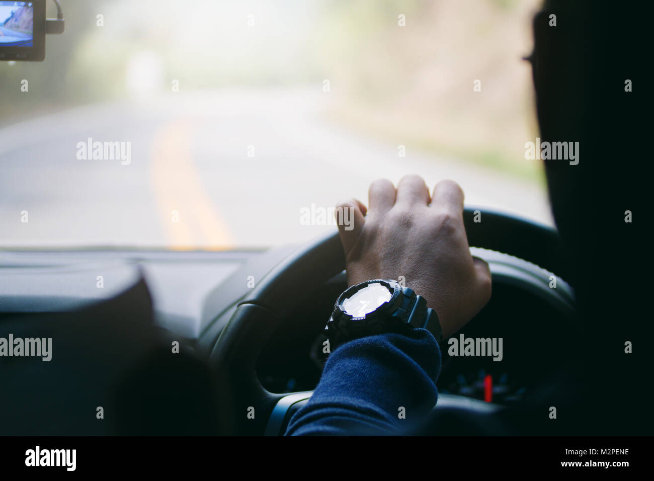 Driver hands holding steering wheel curve road, inside of a car process Stock Photo