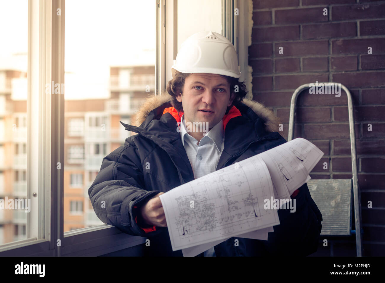 Construction engineer in hardhat with project in hands. Soft focus, toned Stock Photo