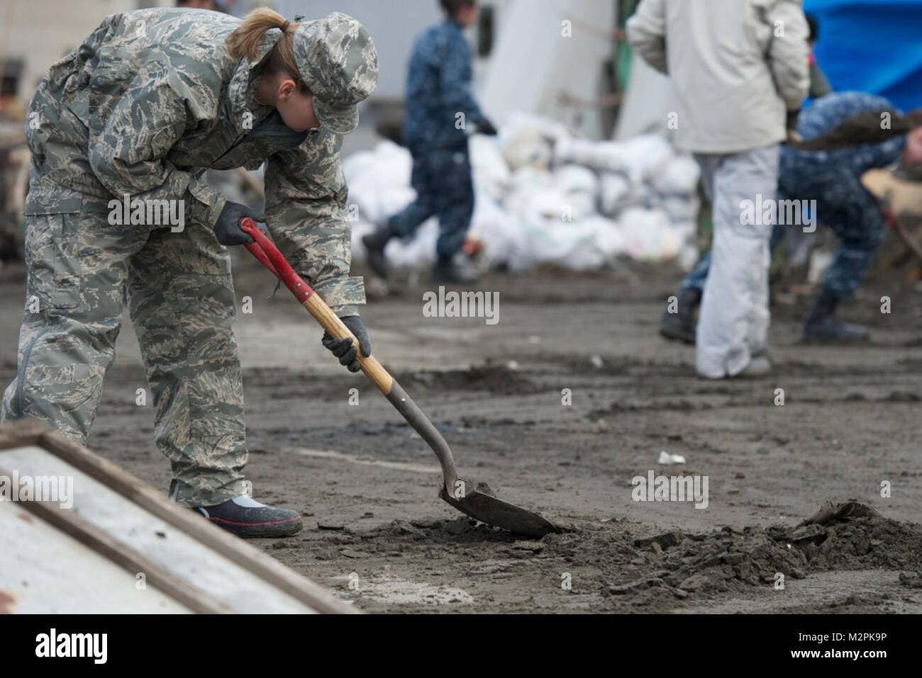 110321-N-9436A-228 HACHINOHE, Japan (March 21, 2011) 2nd Lt. Christina Heino from Hydepark, N.Y., assigned to the 301st Intelligence Squadron, shovels sediment out of the street during relief efforts in this tsunami-battered city. More than 130 volunteers from Misawa Air Base and members of the French Army and Fire Department assisted in a cleanup effort in the northern Japanese city that was devastated by a 9.0-magnitude earthquake that triggered a devastating tsunami on Japan's eastern coastline. (U.S. Navy photo by Cryptologic Technician (Collection) 2nd Class Thomas Ahern/Released) 110321- Stock Photo