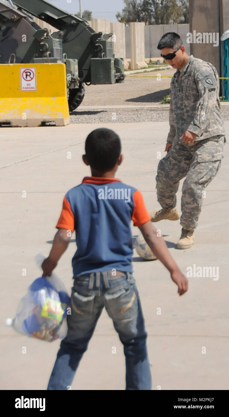 A little football. JOINT BASE BALAD, Iraq – 1st Lt. Jae Kim, executive officer of Battery A, 2nd Battalion, 11th Field Artillery Regiment, 2nd Advise and Assist Brigade, 25th Infantry Division, U.S. Division North, kicks a soccer ball around with a local Iraqi child during an Iraqi Kids Day, March 26, 2011, at Joint Base Balad, Iraq. Kim, a Fort Lee, N.J., native, participated in Iraqi Kids Day with other members of 2nd Bn., 11th FA Regt. Since the summer of 2010, U.S. Soldiers of Joint Base Balad have hosted Kids Day, offering kids and local Iraqis a rare glimpse in the lives of U.S. troops o Stock Photo