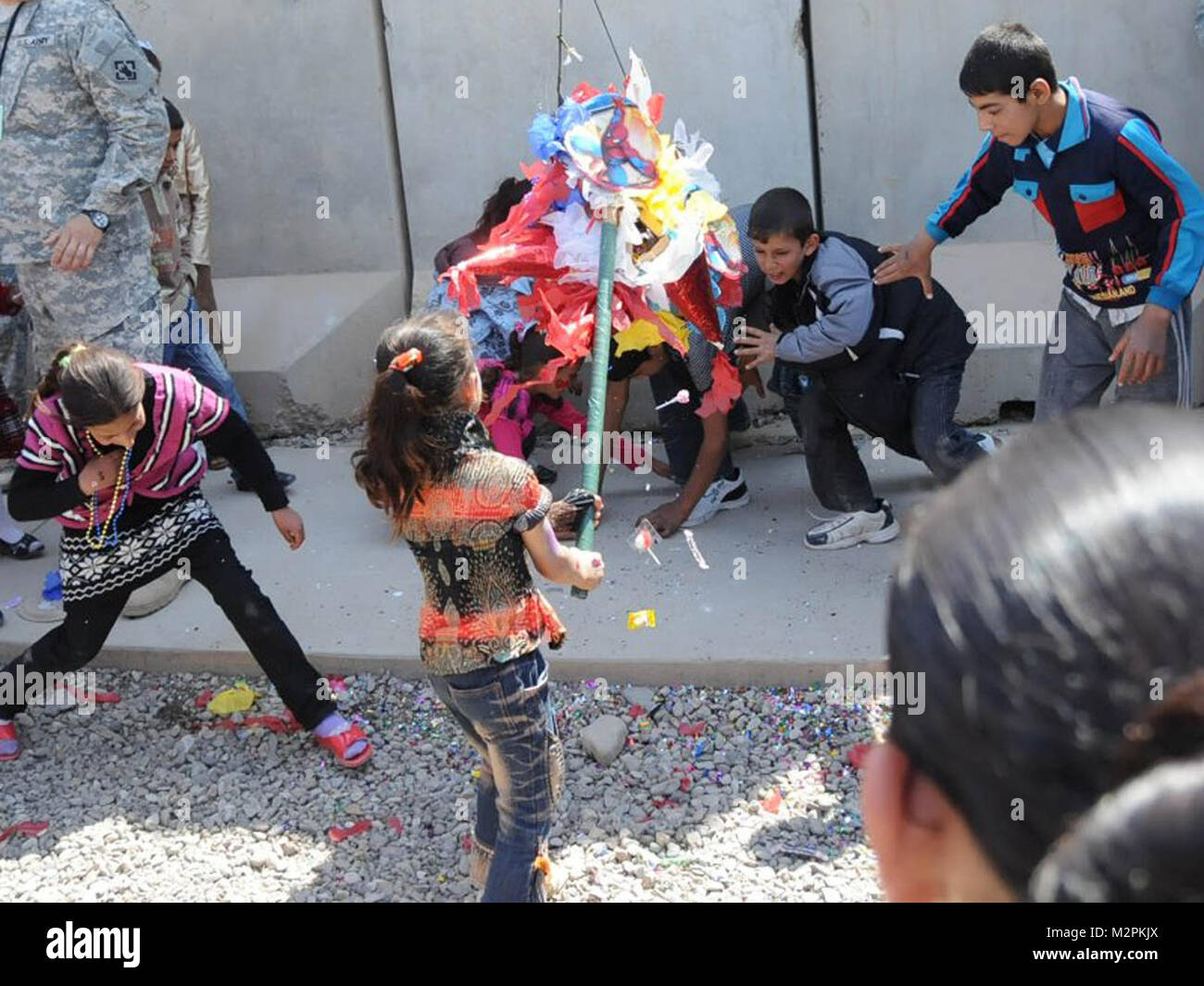 Smash and grab. JOINT BASE BALAD, Iraq – A local Iraqi girl breaks open a piñata during an Iraqi Kids Day, March 26, 2011, at Joint Base Balad, Iraq. Since the summer of 2010, units serving at Joint Base Balad have hosted Kids Day. Hosted by U.S. Soldiers of 2nd Brigade, 25th Infantry Division, approximately 100 Iraqi children participated in the day’s events, to include rappel rides, face painting, sport activities, and a piñata filled with candy and toys.  (U.S. Army photo by Staff Sgt. Ricardo Branch, 2nd AAB PAO, 25th Inf. Div., USD-N) Smash and grab by United States Forces - Iraq (Inactiv Stock Photo