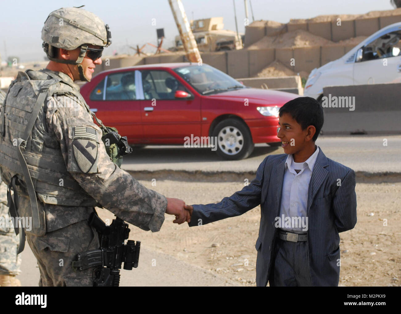 Shaking Hands CONTINGENCY OPERATING SITE WARRIOR, Iraq – Spc. Shane Darst, an armor crewmember serving with Company D, 2nd Battalion, 12th Cavalry Regiment, attached to the 1st Advise and Assist Task Force, 1st Infantry Division, shakes hands with a young child at a checkpoint near Contingency Operating Site Warrior, Iraq, April 3, 2011.  (U.S. Army photo by Staff Sgt. Robert DeDeaux, 1st AATF PAO, 1st Inf. Div., USD-N) Shaking Hands by United States Forces - Iraq (Inactive) Stock Photo