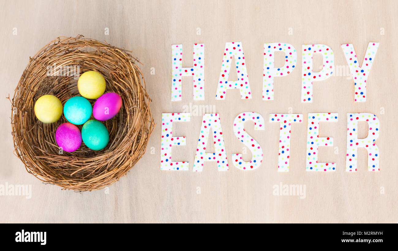 Bright colorful Easter eggs in a rustic nest or basket on wooden ...