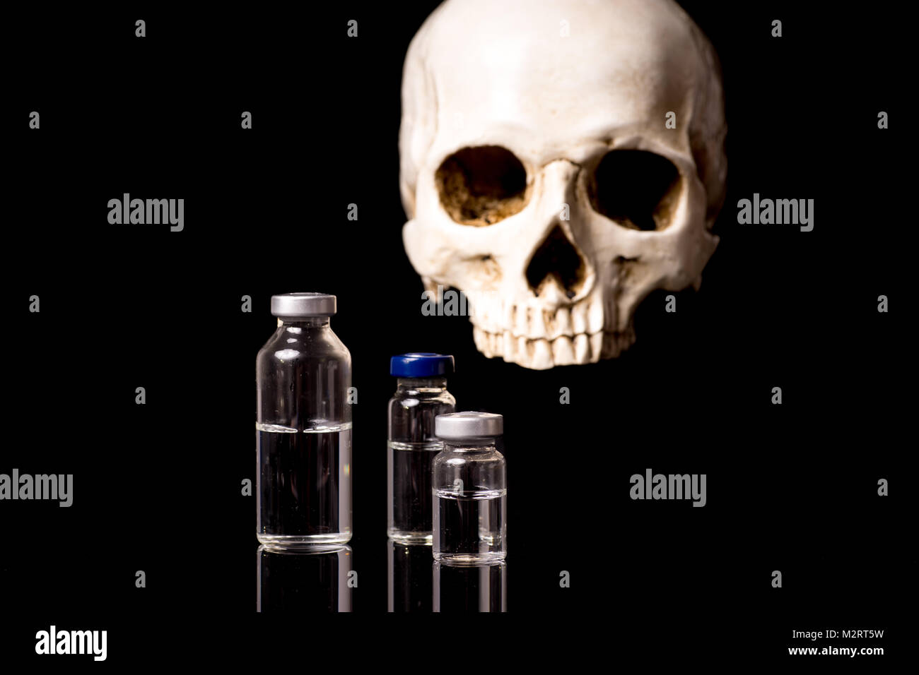 medical vials and blurry skull isolated on black background Stock Photo