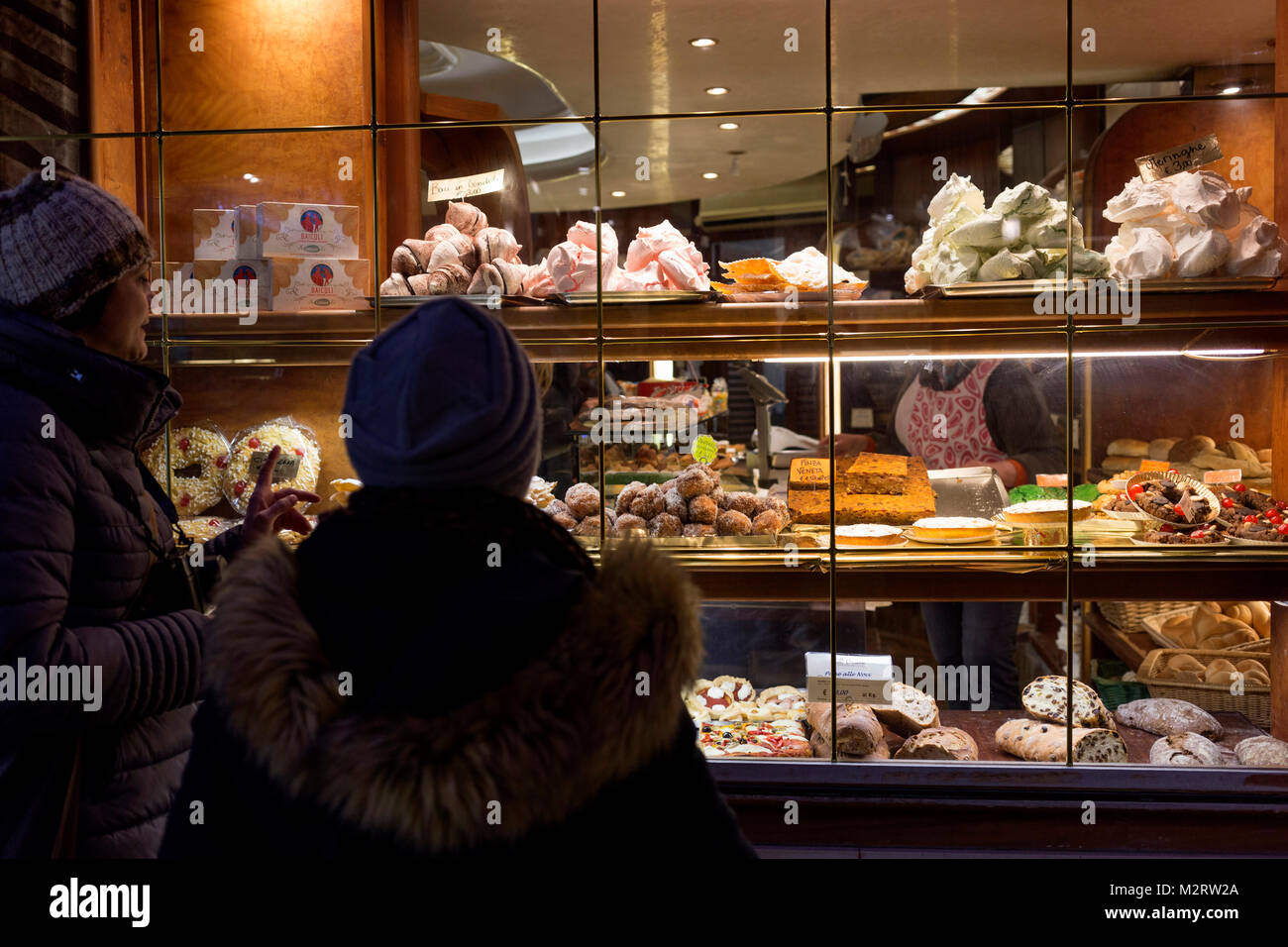 Two women looking at cakes in the window of a pastry shop in Venice Stock Photo