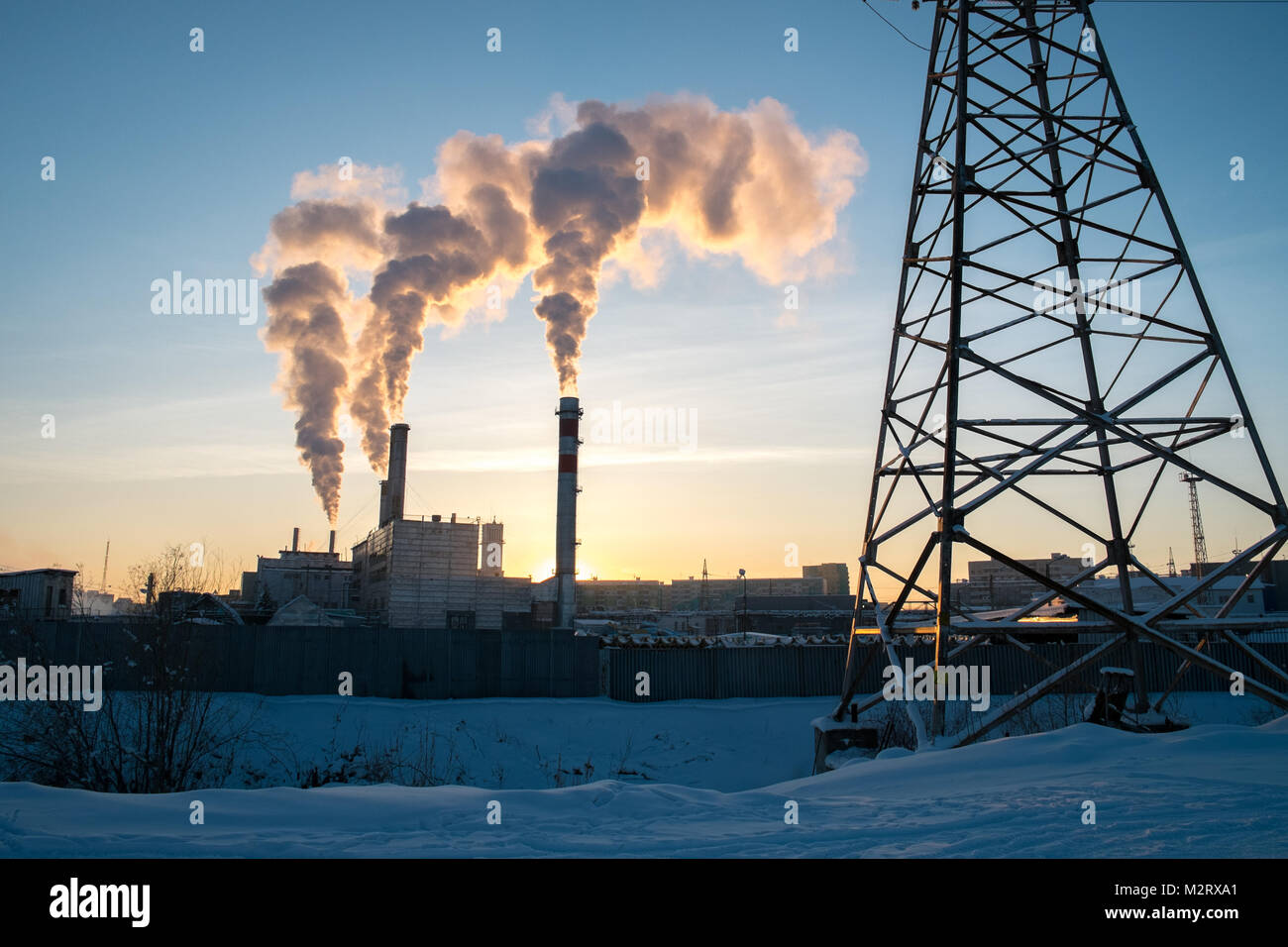 A plant providing heating for the people of Yakutsk in Siberia releases smoke into the air as dusk falls. Yakutsk is the second coldest major city in  Stock Photo