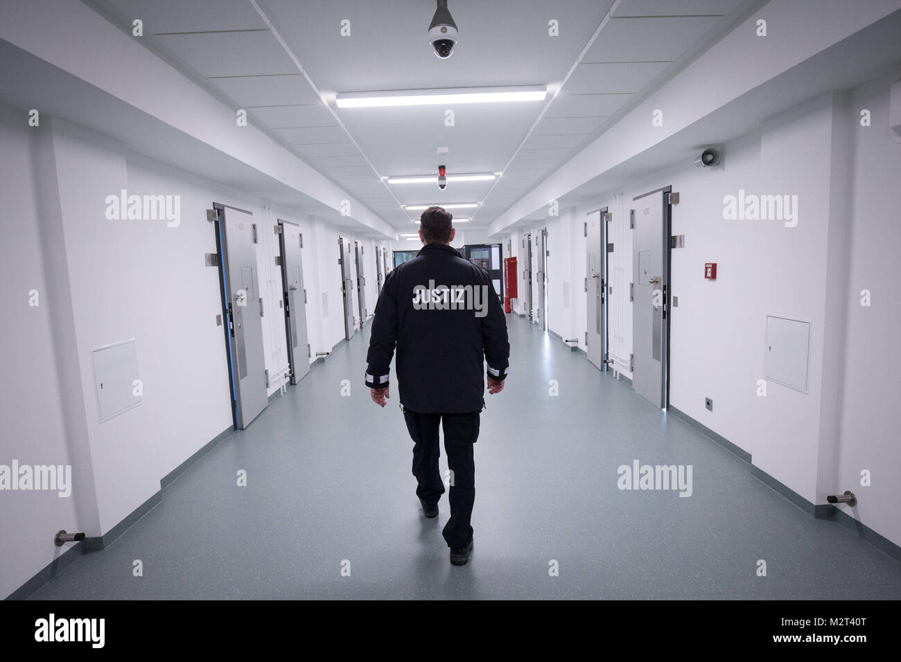 Hamburg, Germany. 08th Feb, 2018. A prison guard walking through the recently renovated B-wing of the Holstenglacis remand centre during a tour for the press in Hamburg, Germany, 08 February 2018. There are 99 cells waiting for inhabitants in a completely modernised wing of Hamburg's Holstenglacis remand centre. The institution, after almost three years of renovation work, now counts with a total of 484 places for prisoners in remand. Credit: Christian Charisius/dpa/Alamy Live News Stock Photo