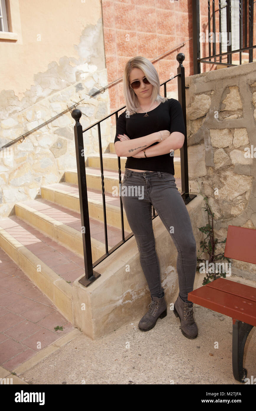 Beautiful blonde girl wearing tight jeans and a black t-shirt outdoors Stock Photo