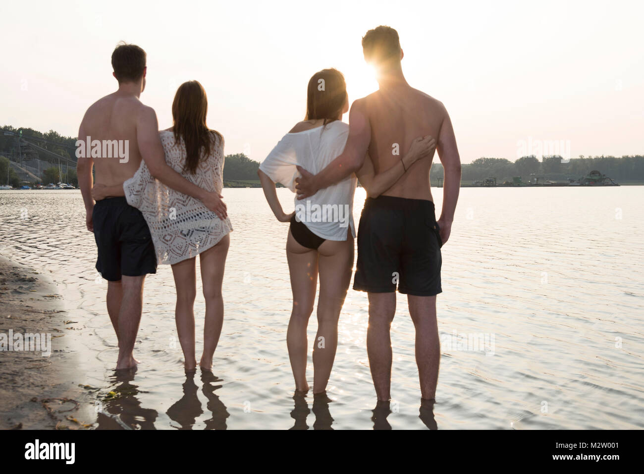 Two young couples in the sundown on the quarry pond Liedolsheim, Dettenheim, Baden-Wurttemberg, Germany Stock Photo
