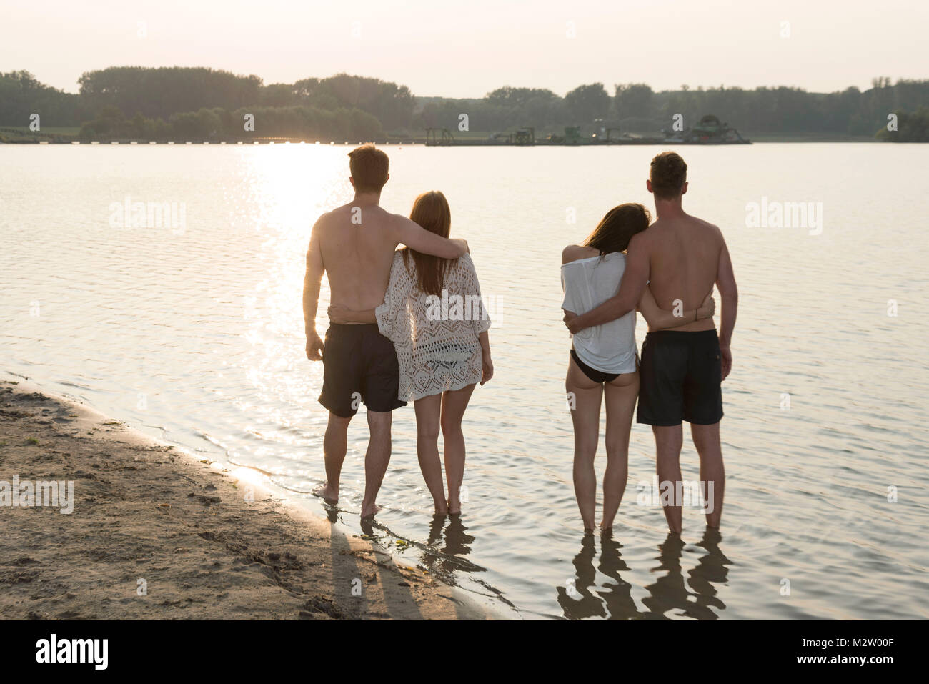 Two young couples in the sundown on the quarry pond Liedolsheim, Dettenheim, Baden-Wurttemberg, Germany Stock Photo