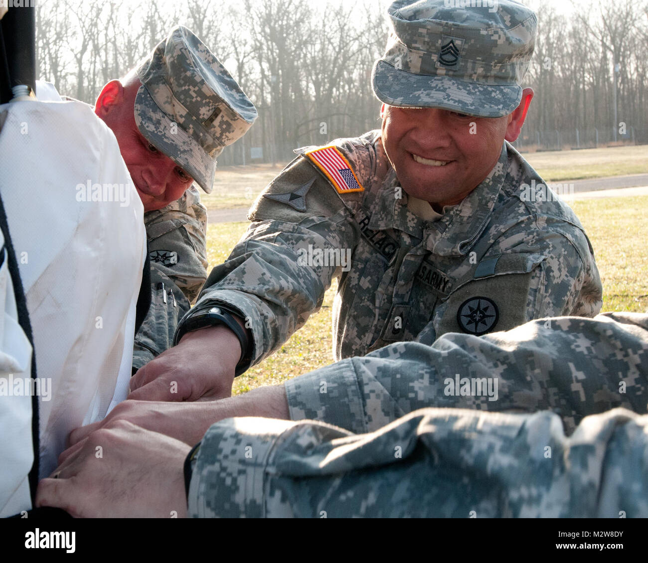 Sgt. 1st Class Nicolas Relacion, a native of West Grove, Pa., and Chief Warrant Officer 2 Shawn McKay, a native of Pittsburgh, both members of the 316th ESC, remove the straps from a large Trailer Mounted Support System tent during the setup process at Fort Dix, N.J., March 19.  These tent systems are the first step in learning how to set up a Tactical Operations Center that will help ensure communication with command and control elements.  (U.S. Army Photo by Army Sgt. Peter J. Berardi, 316th Sustainment Command (Expeditionary)) Sgt. 1st Class Relacion Helping to Unstrap a Large Tent by 316th Stock Photo