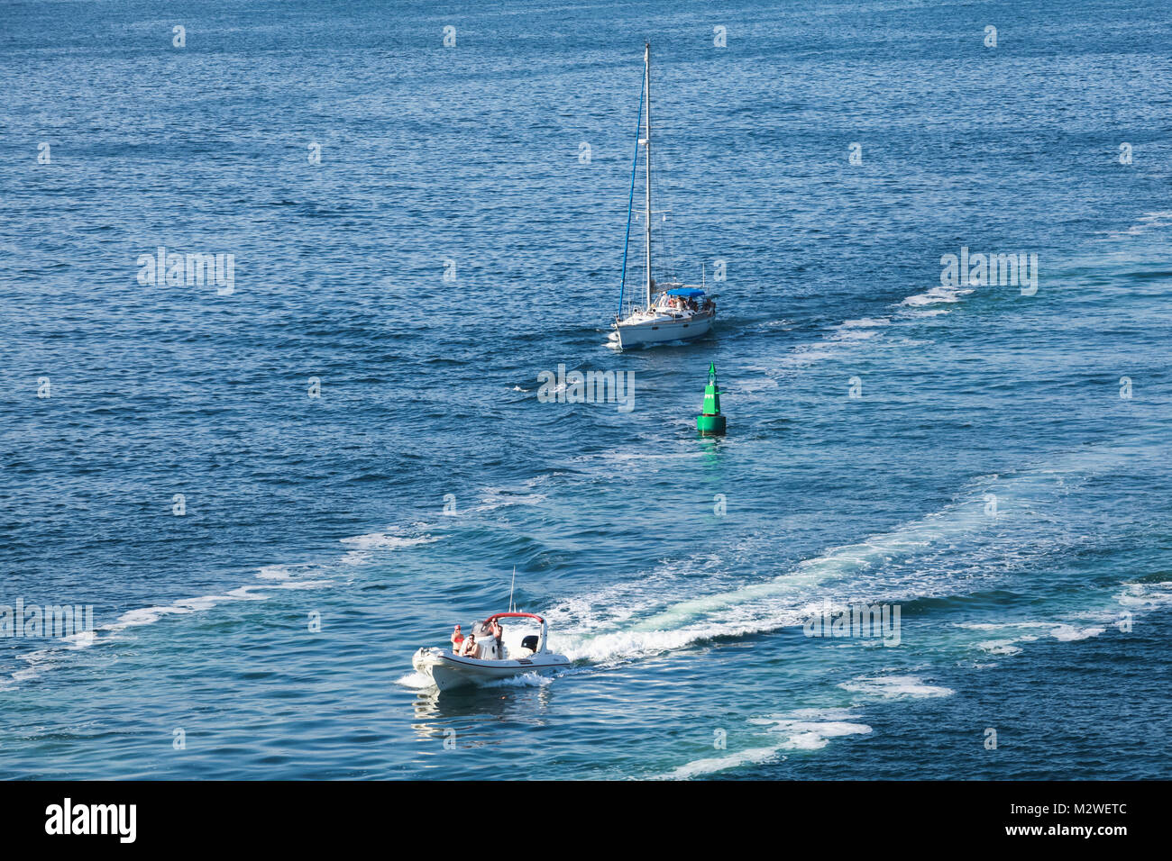 Corsica, France - July 2, 2015: Pleasure motor boat and sailing yacht with passengers go on fairway Stock Photo
