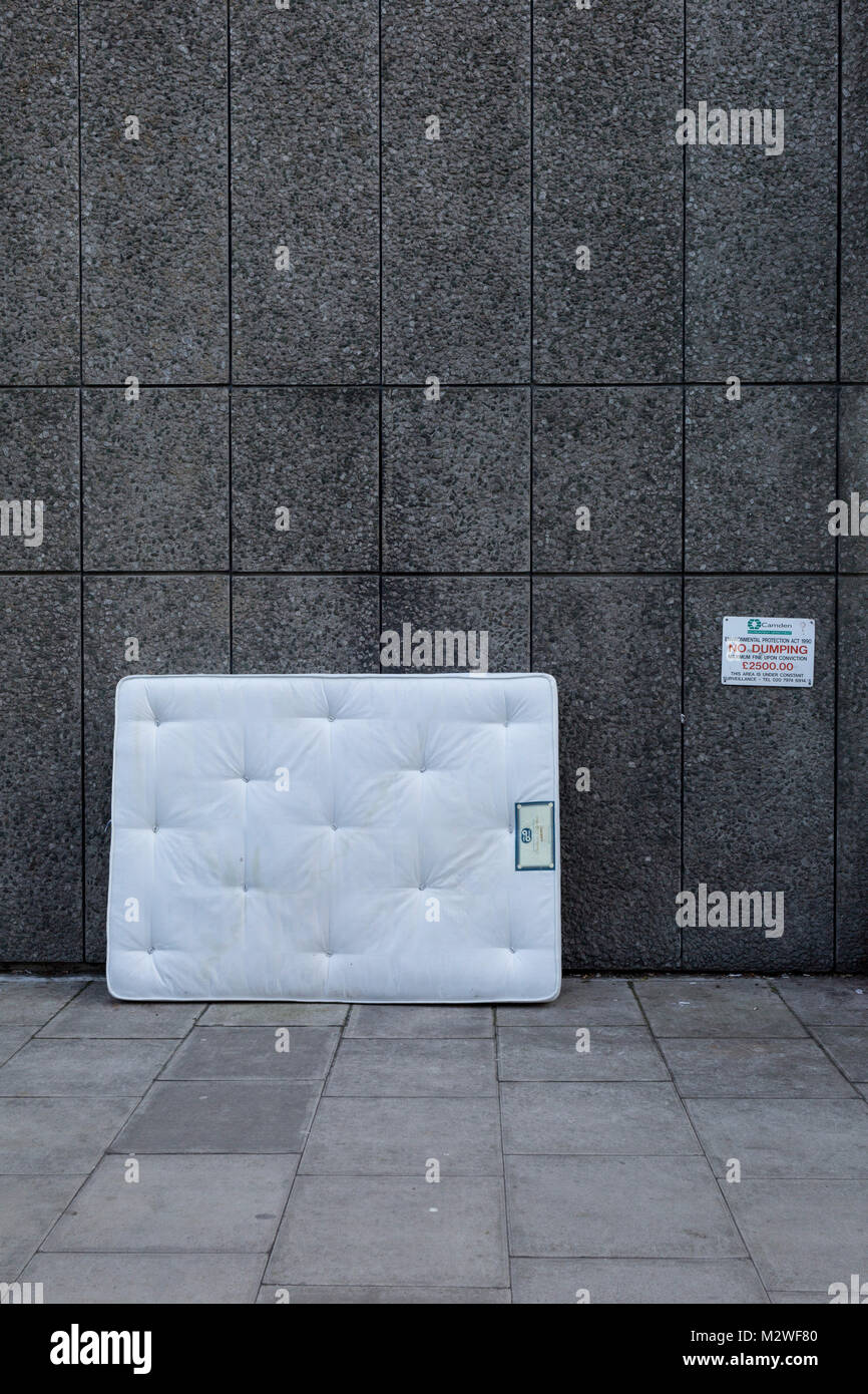 A stained white mattress leans against a wall next to a sign warning of  £2,500 fines by the local authority for dumping or fly-tipping, on 6th  February 2018, in the borough of