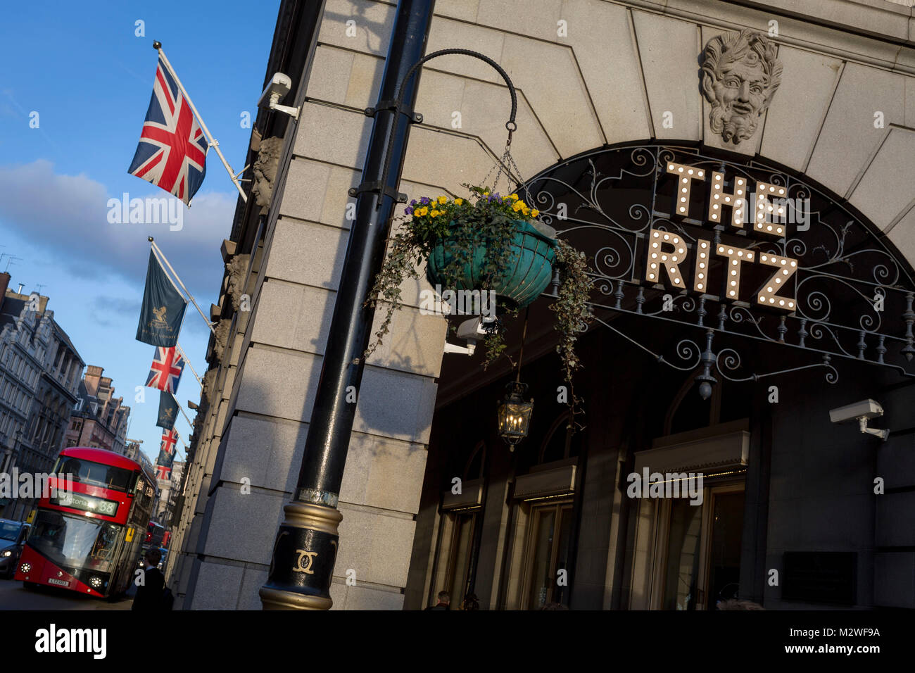 The entrance of the arcade outside The Ritz with Union Jack flags, a Routemaster bus and distant architecture on Piccadilly, on 7th February 2018, in London, England. Stock Photo