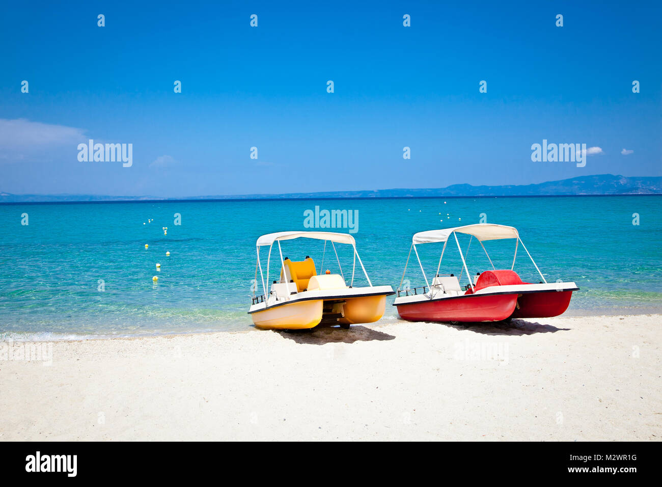 Beautiful Hanioti beach with Colorful pedalos docked on Kasandra peninsula, Halkidiki,  Greece. Stock Photo