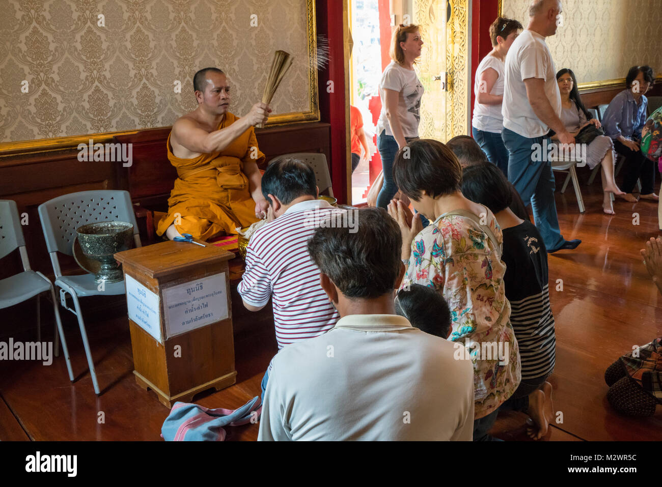 The monk with Faithful in Wat Traimit temple in Bangkok Stock Photo