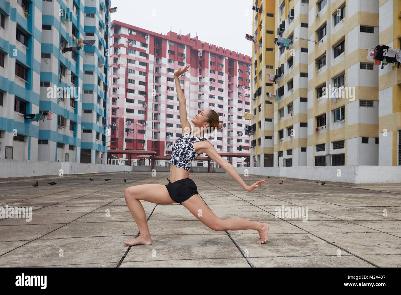 Young female dancer dancing in the city with colourful buildings in the background in Singapore. Stock Photo