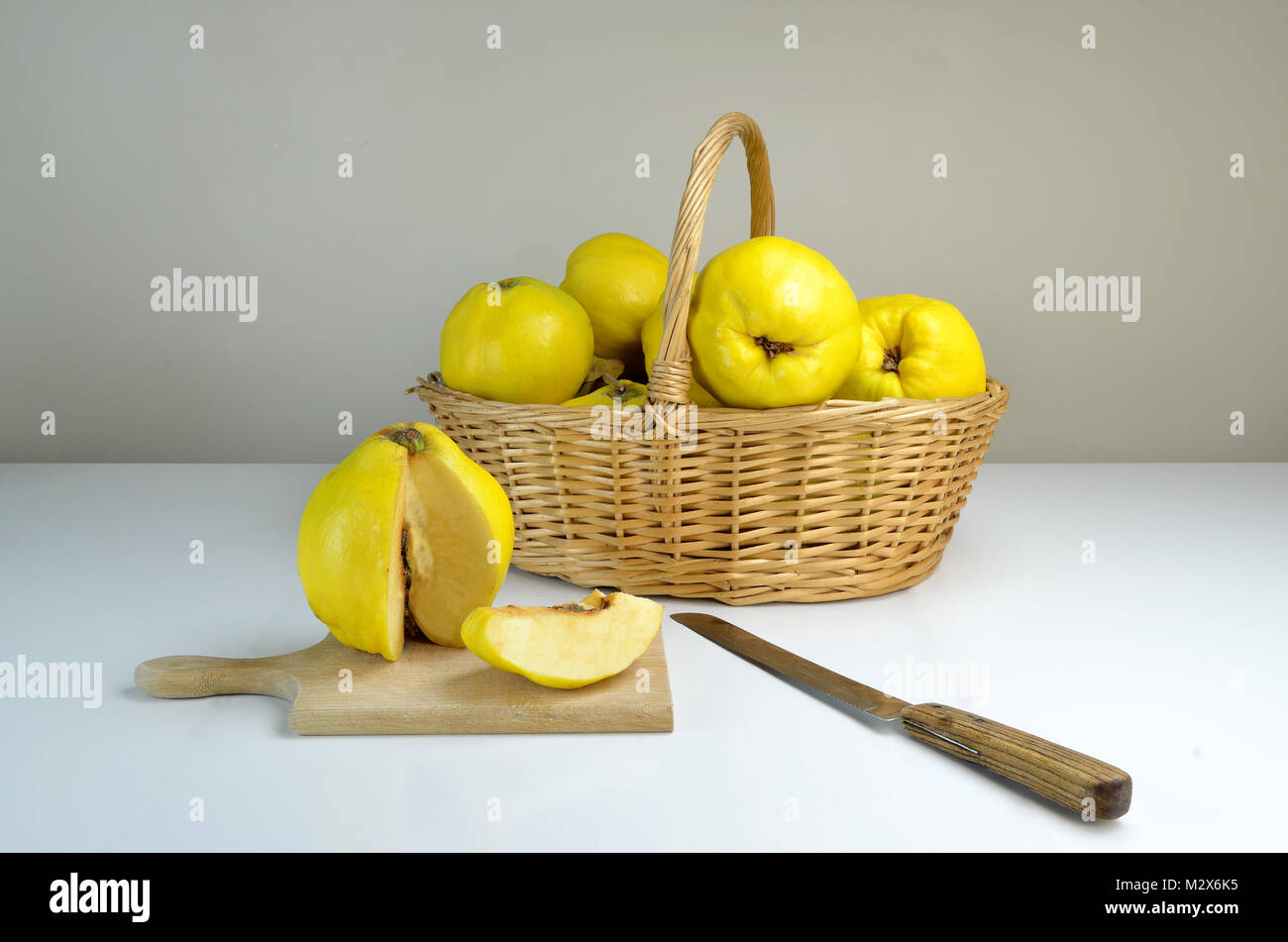 Composition of basket of quinces on a white table Stock Photo