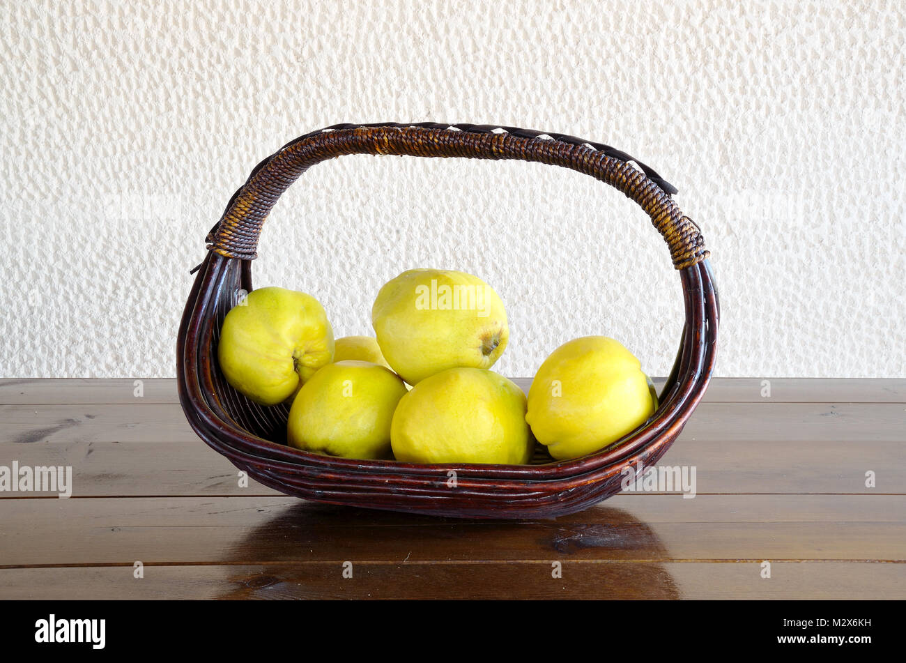 Basket of quinces on a wooden table Stock Photo