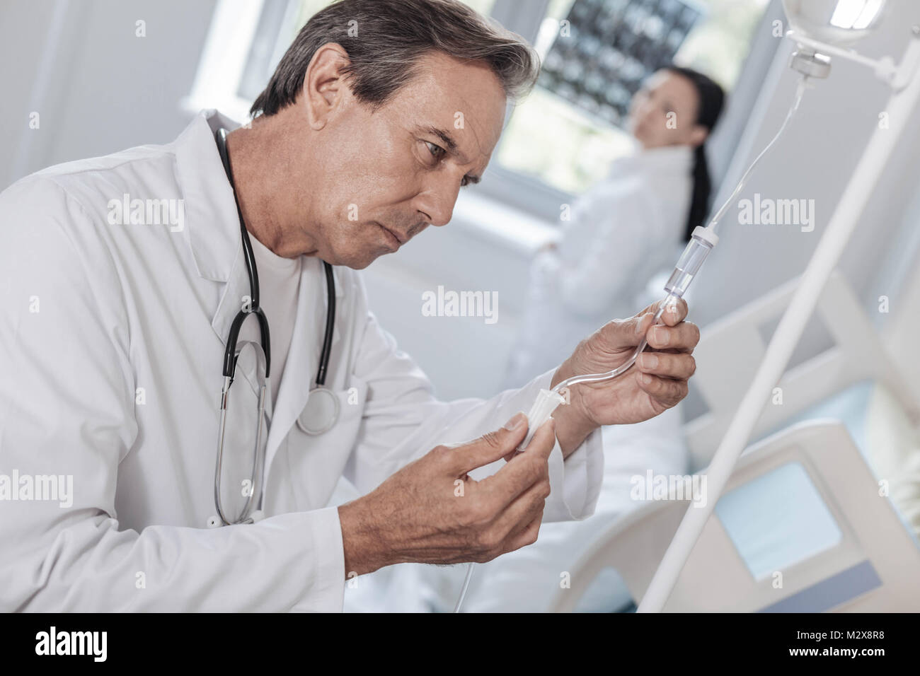 Concentrated physician checking drop counter in hospital Stock Photo