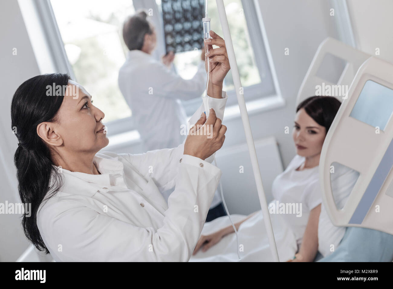 Joyful female medical worker adjusting drop counter Stock Photo