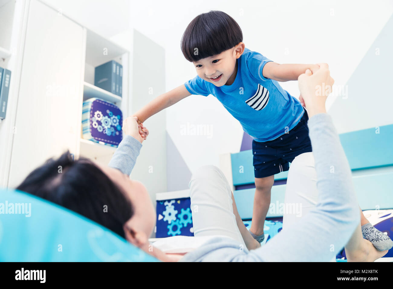 Lovely boy and mother play in the bedroom Stock Photo