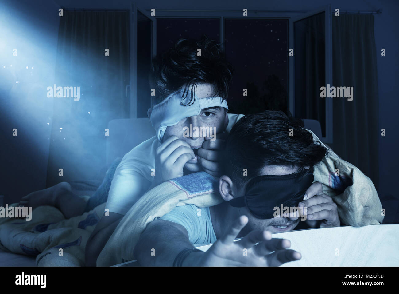 scared and sleepless boys chewing fingernails at bedroom in front of shiny moon Stock Photo
