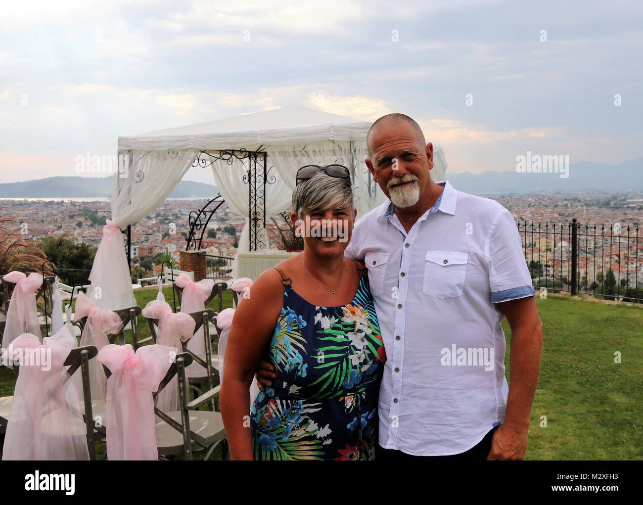 A mature couple on vacation at a wedding with the town of Fethiye in the background , turkey, 4th august 2017 Stock Photo