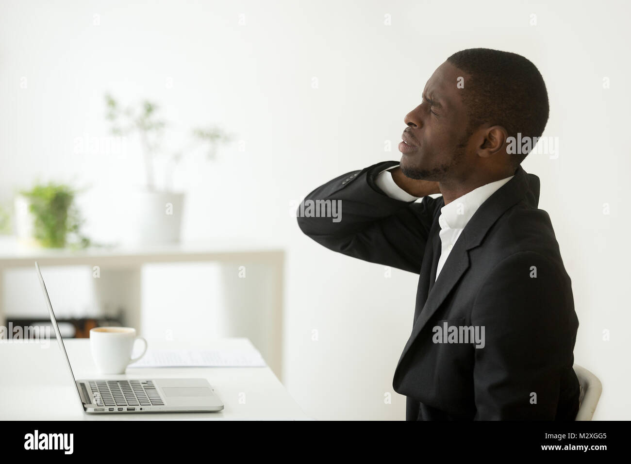 African american businessman feels neck pain sitting on uncomfortable office chair at work, black man having computer syndrome suffering from stiff ne Stock Photo